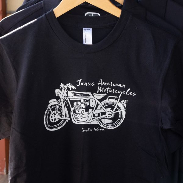 Black t-shirt with Janus American Motorcycles graphic design hanging on a rack.