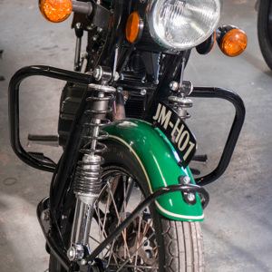 Classic green motorcycle front view showing headlight and suspension.