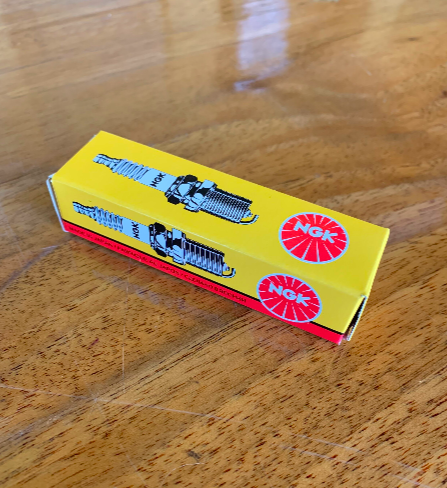 Yellow box of Nik Nak brand toy train on wooden floor.