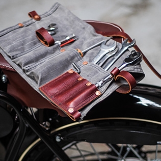 Leather and canvas motorcycle tool roll on a black bike.