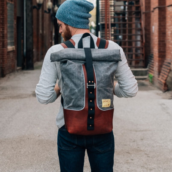 Man with stylish canvas backpack walking in urban alley.