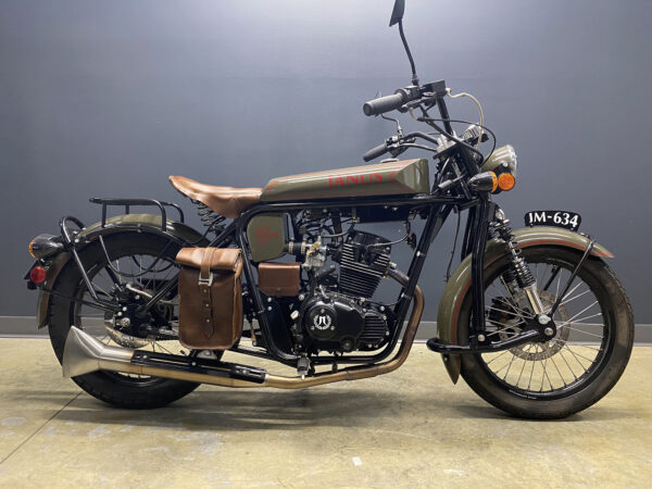 Vintage-style motorcycle with leather saddlebags parked indoors.