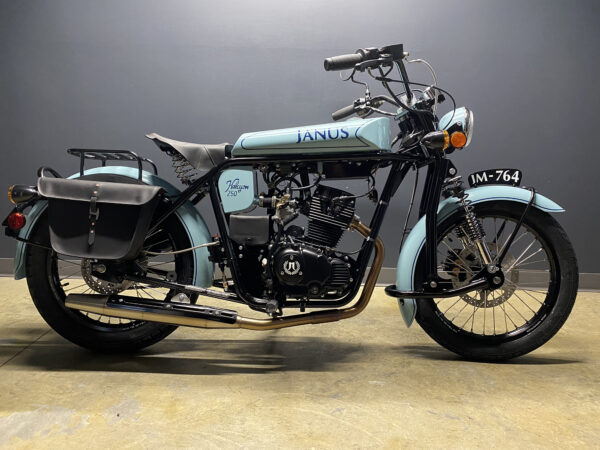 Vintage Janus motorcycle with side saddlebag parked indoors.