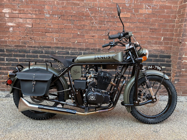 Vintage-style motorcycle with sidecar parked against brick wall.