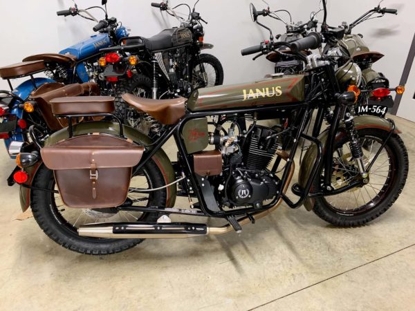 Collection of classic Janus motorcycles with leather saddlebags on display.