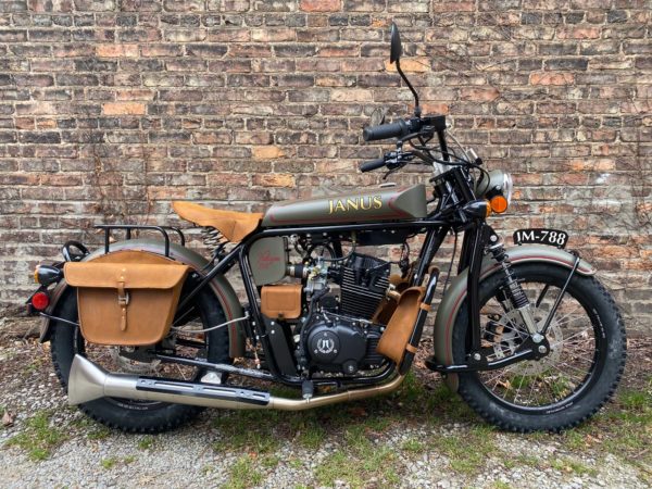 Vintage-style Janus motorcycle with sidecar parked against a brick wall.