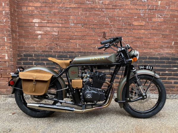 Vintage Janus motorcycle parked against a brick wall.