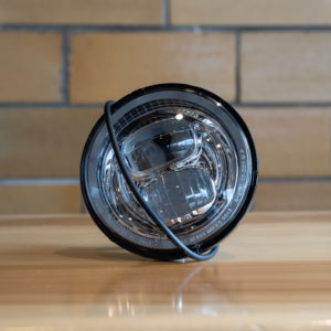 Black round car headlight on wooden surface.