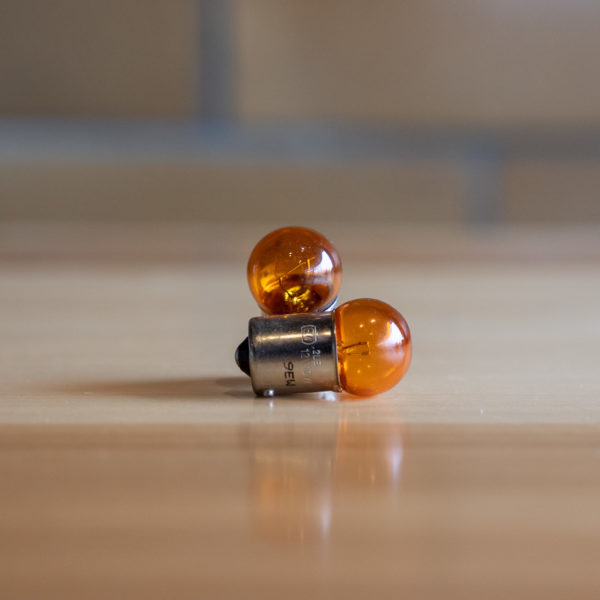 Amber-colored, spherical automotive bulbs on a wooden surface.