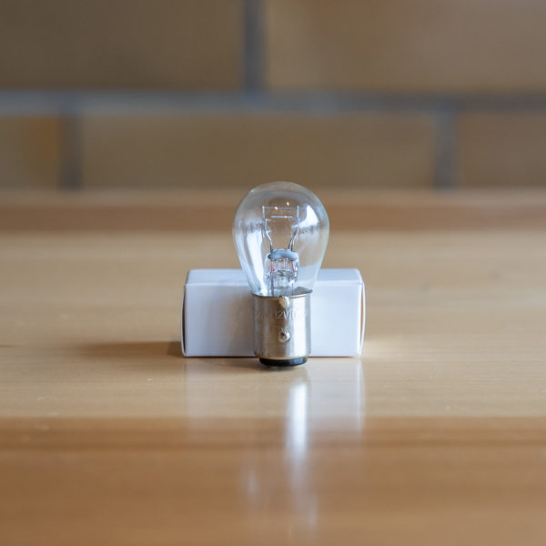 Clear incandescent bulb on white socket against a wooden surface.