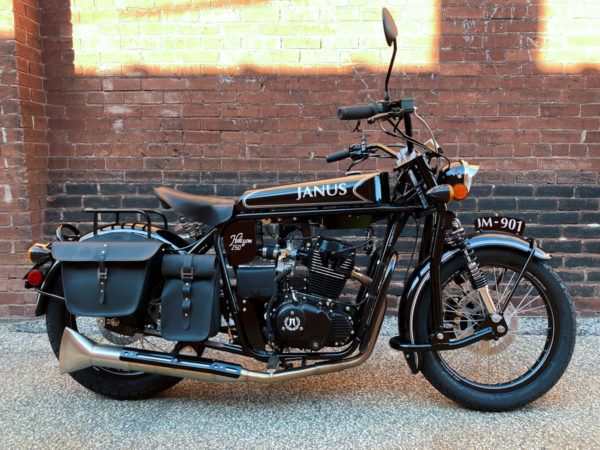 Black Janus Halcyon 250 motorcycle parked by a brick wall.