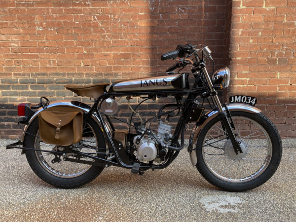 Classic motorcycle with leather saddlebags parked against a brick wall.