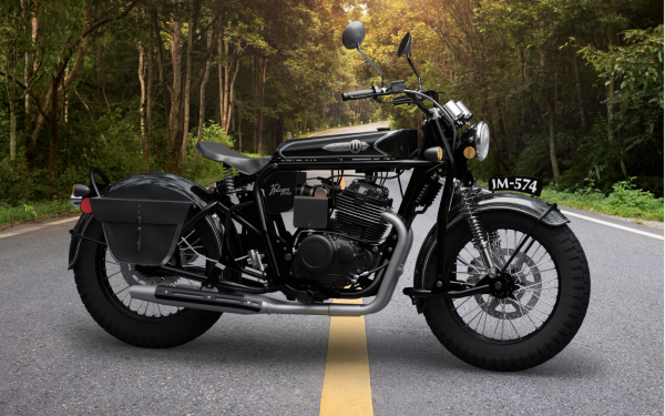Classic black motorcycle parked on a forest road with yellow dividing line.