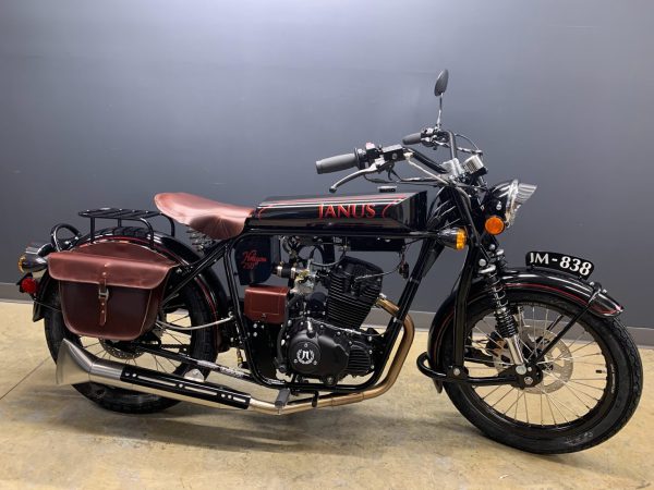 Classic black motorcycle with tan leather seats and saddlebags against a dark background.