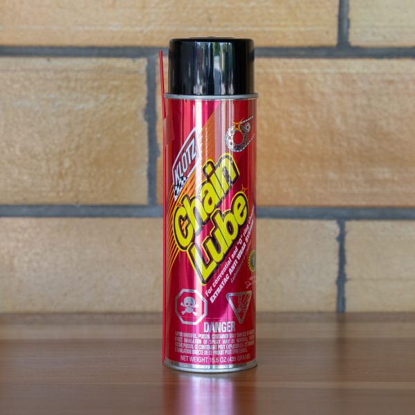 Red can of chain lubricant spray on a wooden background.