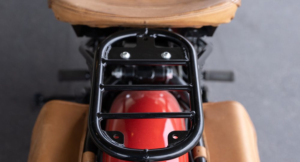 Close-up of red motorcycle's rear with brown leather seat and luggage rack.