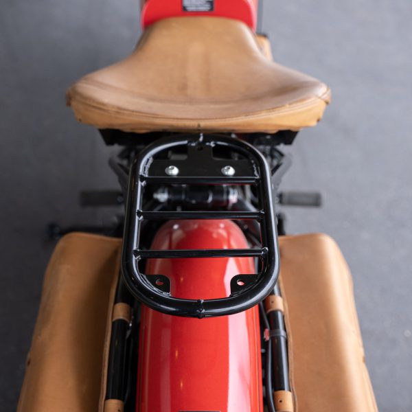 Close-up of red motorcycle's rear with brown leather seat and luggage rack.