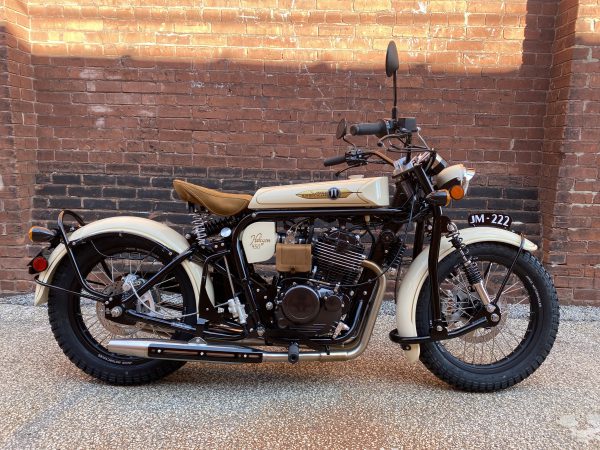 Classic motorcycle parked in front of a brick wall.