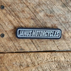 Janus Motorcycles patch on wooden background.