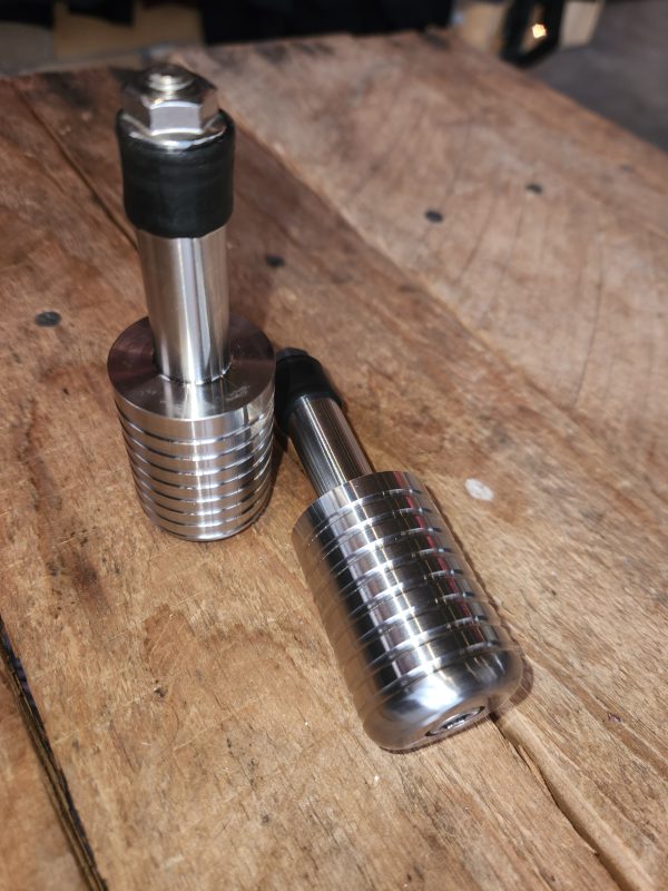Stainless steel espresso tampers on wooden table.
