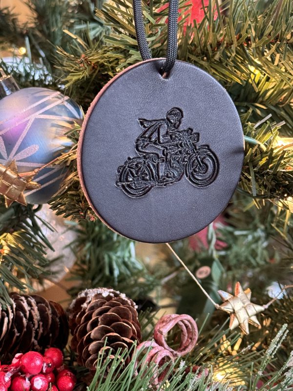 Motorcycle-themed Christmas ornament hanging on a festive tree.
