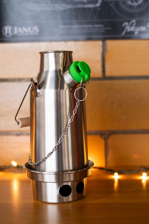 Stainless steel water bottle with green lid and chain on a wooden surface, warm lighting.