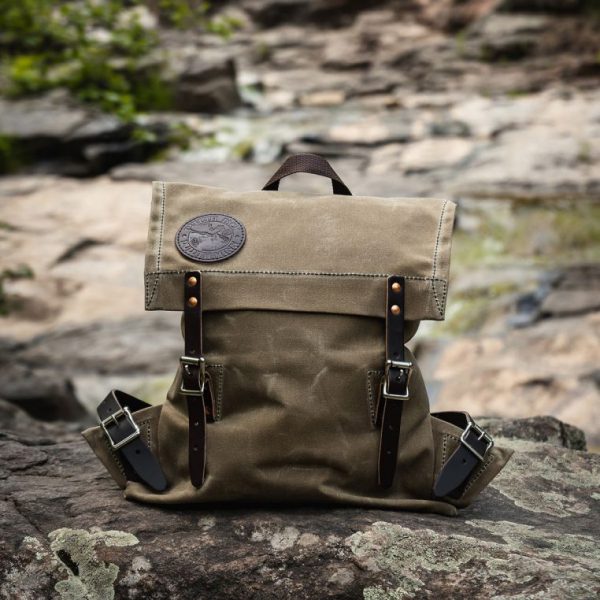 Canvas backpack with leather straps on rocky terrain.