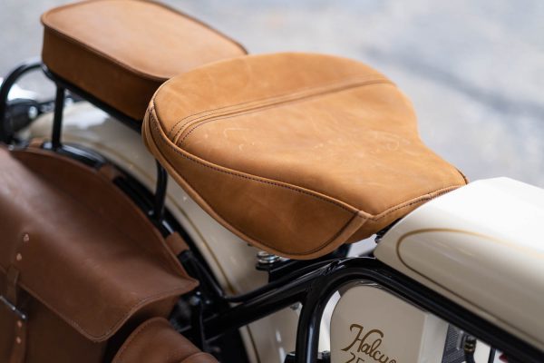 Close-up of tan leather motorcycle seats with white fuel tank visible.