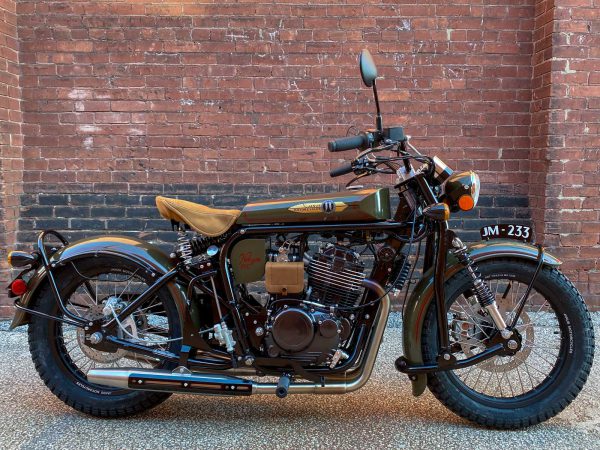 Vintage motorcycle parked against a brick wall.